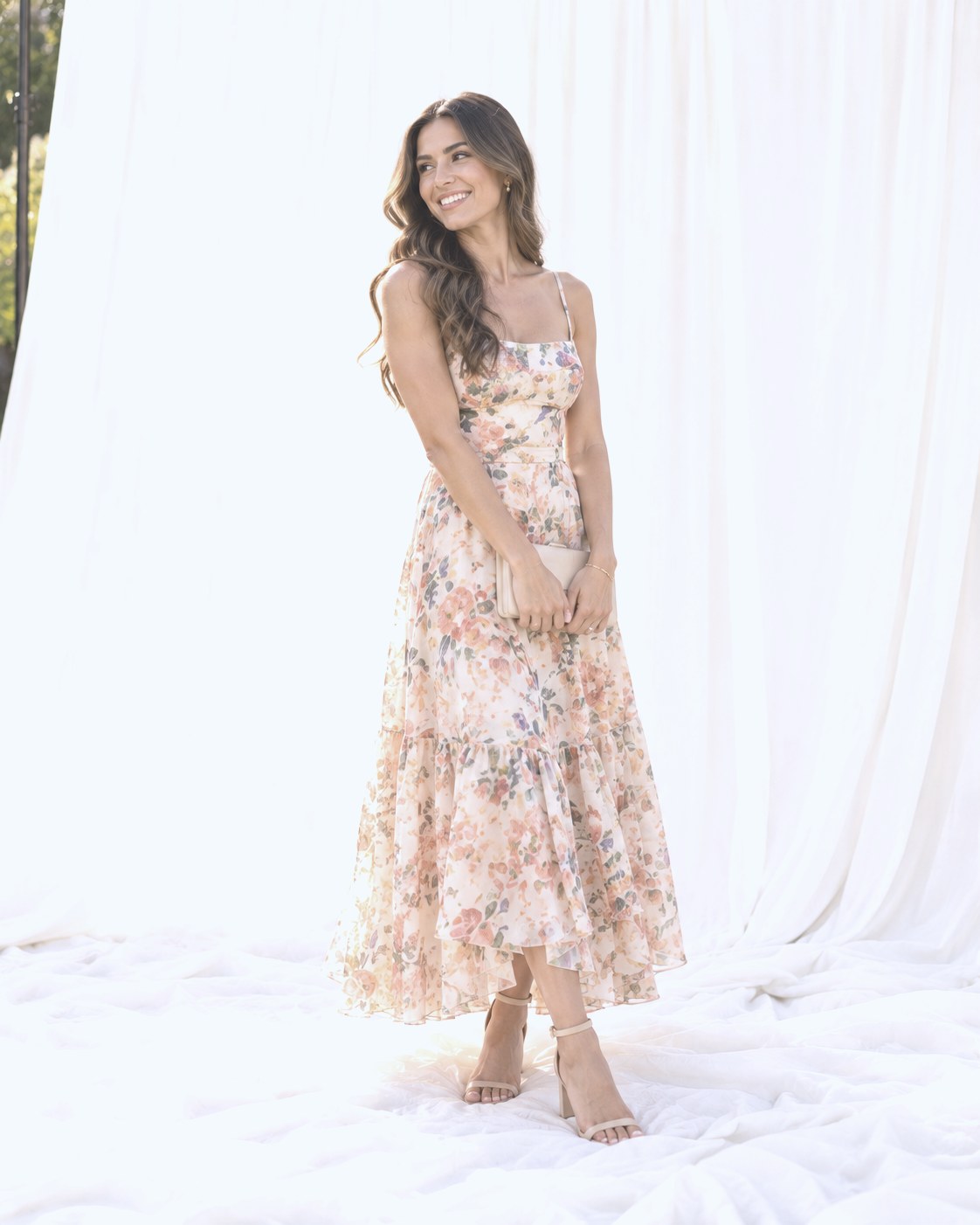 Full-length portrait of a smiling guest in a floral midi dress on the white backdrop