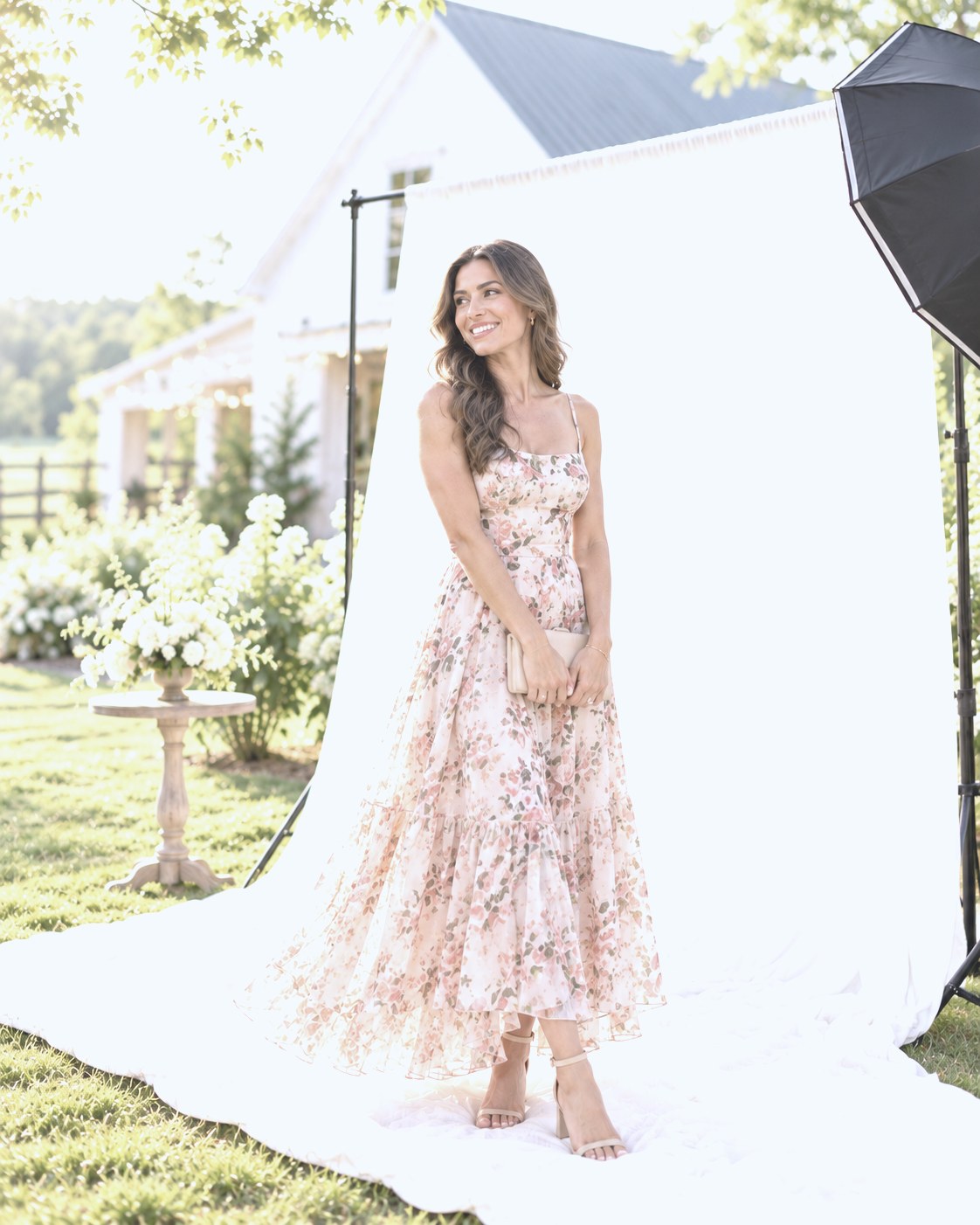 Guest in a blush floral midi dress smiling on the backdrop