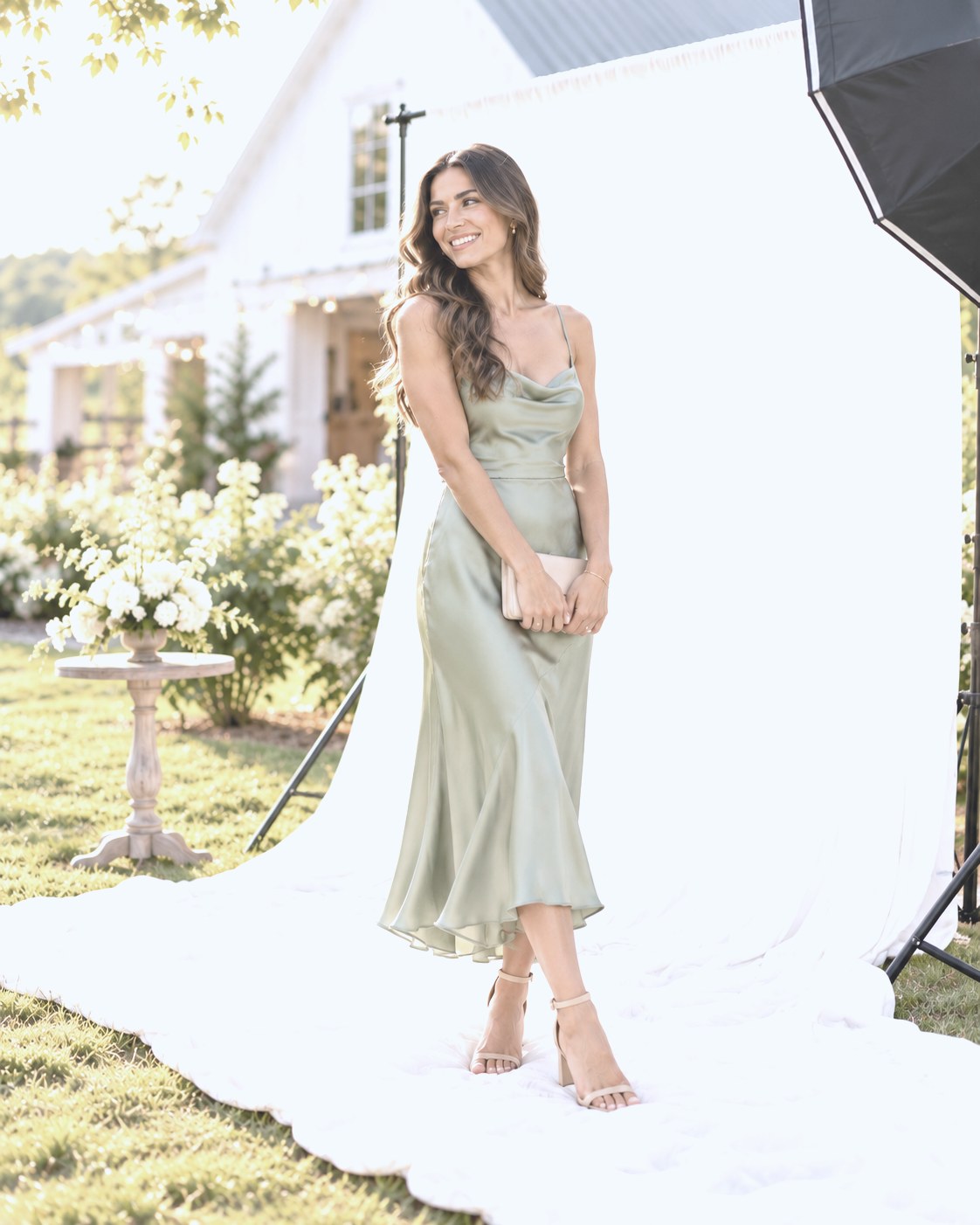 Guest in a sage satin slip dress posing on the backdrop