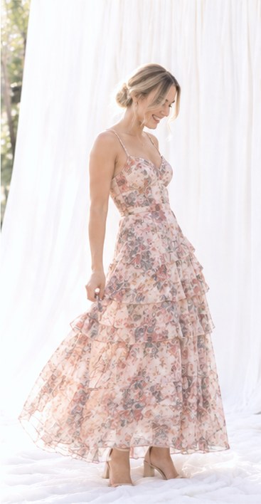 Guest in a blush tiered floral dress twirling her skirt